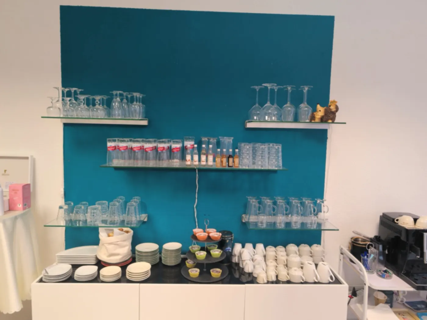 Kaffeebar mit Tassen und Gläsern vor der türkisen Wand